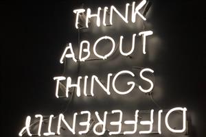 White neon sign on a black background "Think about things differently" with the last word upside down